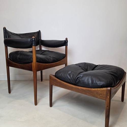 Kristian Solmer Vedel armchair and footstool set featuring sculptural Brazilian rosewood frames, curved armrests, and original black leather upholstery, Denmark, mid‑century modern design